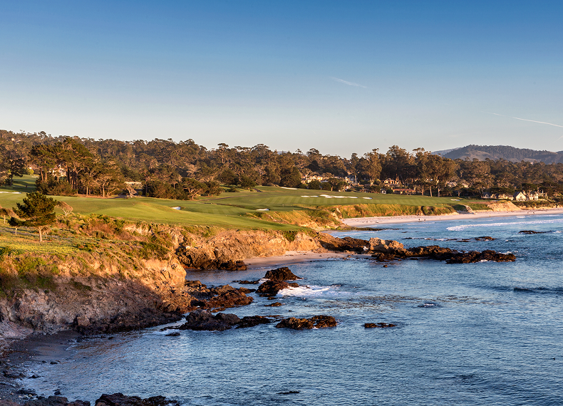 A scenic view of the Pebble Beach golf course running along the rocky cliffs and coastline during golden hour.